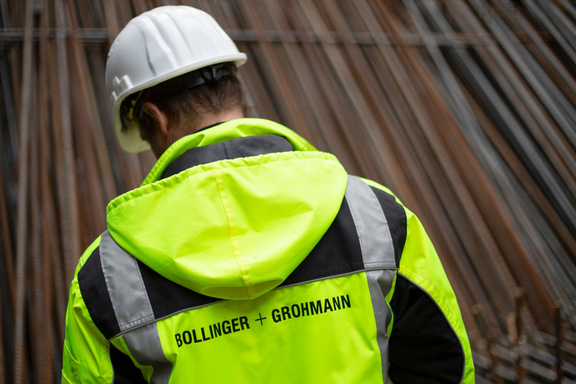 Man from B+G with helmet and safety vest from behind