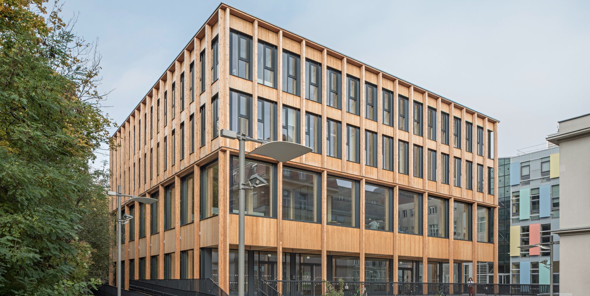 A rectangular four-storey building with a wooden façade and floor-to-ceiling windows